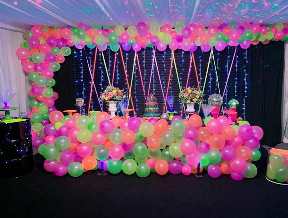 Backdrop con luces globos y materiales neón para mesa principal